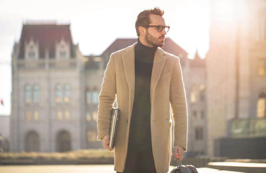 Photo by Andrea Piacquadio Fashionable young man with a laptop walking in the sunlight near a historic building in Budapest.